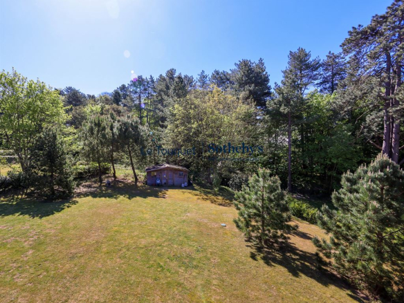 View of a garden with a wooden chalet surrounded by trees in Hardelot.