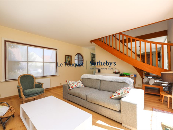 Interior of a house with a bright living room and a wooden staircase.
