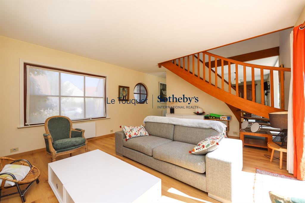Interior of a house with a bright living room and a wooden staircase.