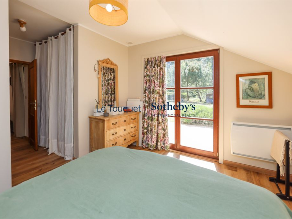 Room in a house with a view of the garden, wooden furniture and warm decor.