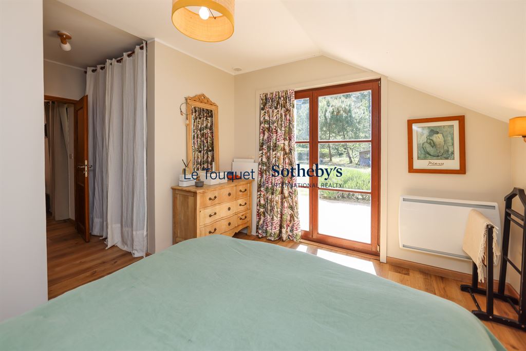 Room in a house with a view of the garden, wooden furniture and warm decor.
