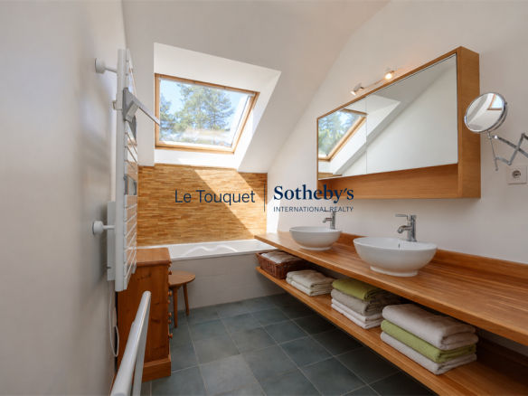 Modern bathroom with bathtub, double sink and natural lighting.