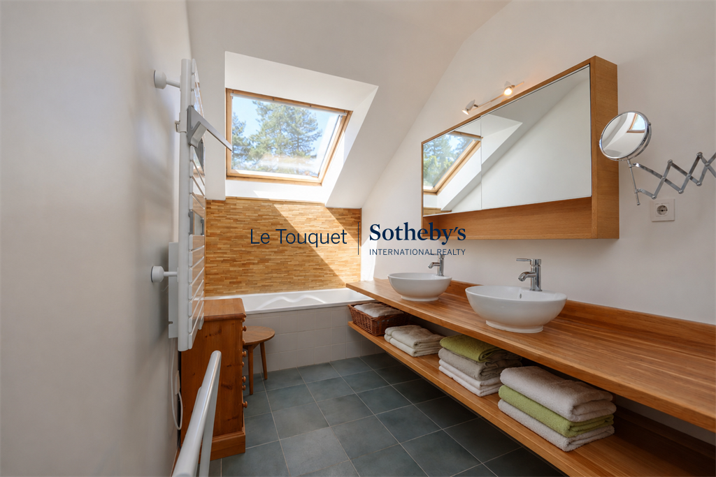 Modern bathroom with bathtub, double sink and natural lighting.