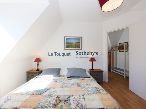 Room with double bed and simple decor, natural light coming in through a window.