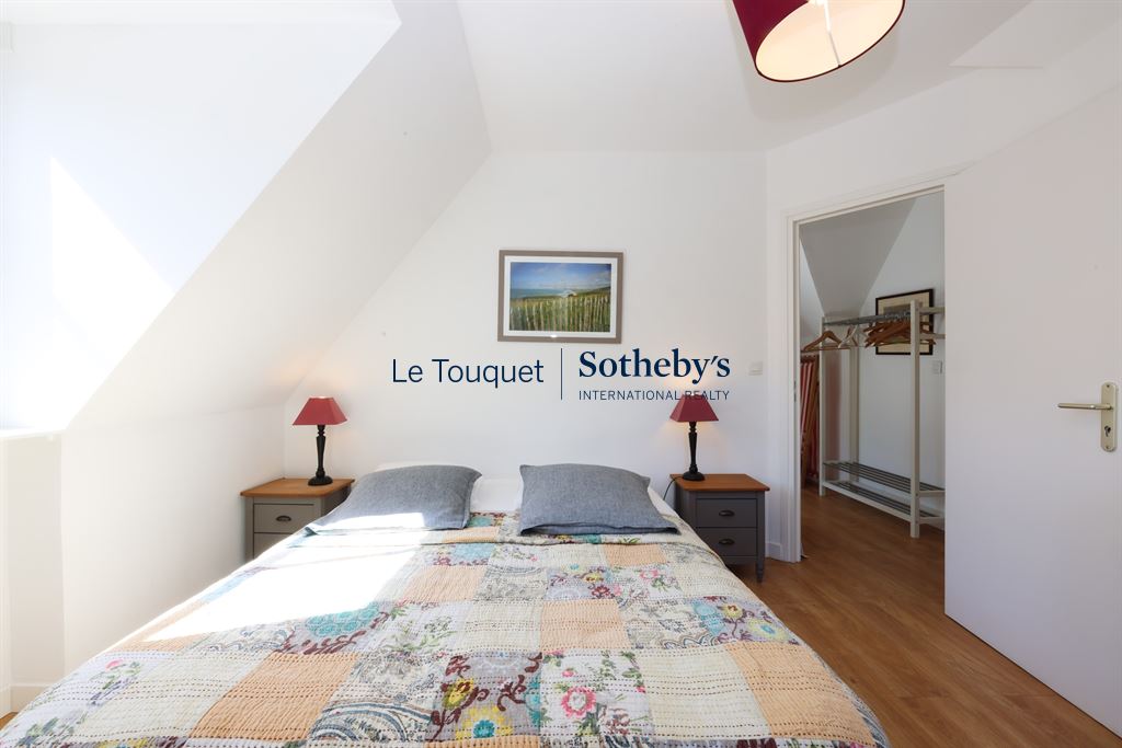Room with double bed and simple decor, natural light coming in through a window.