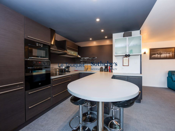 Modern kitchen in an apartment in Le Touquet with central island and integrated appliances.