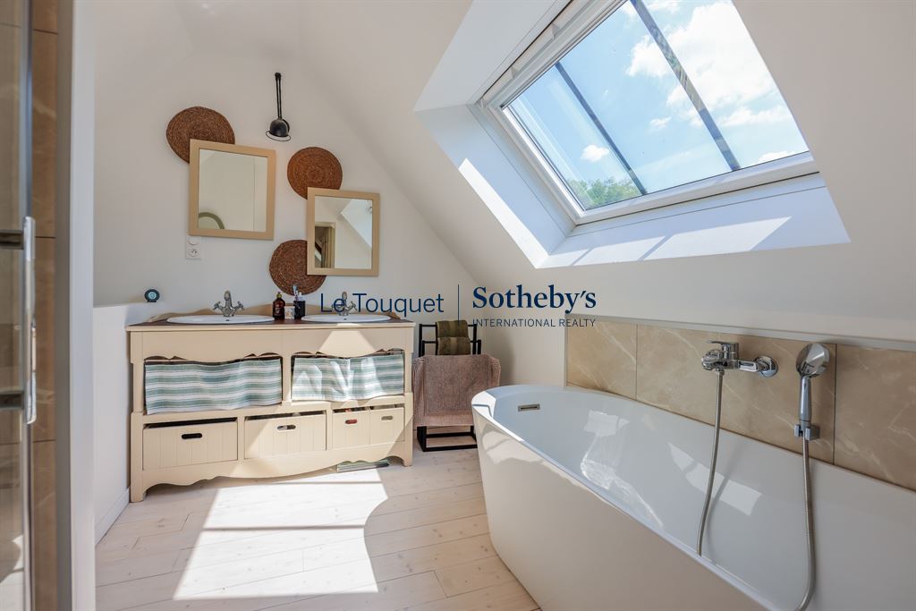 Modern bathroom with bathtub and skylight in a renovated property.