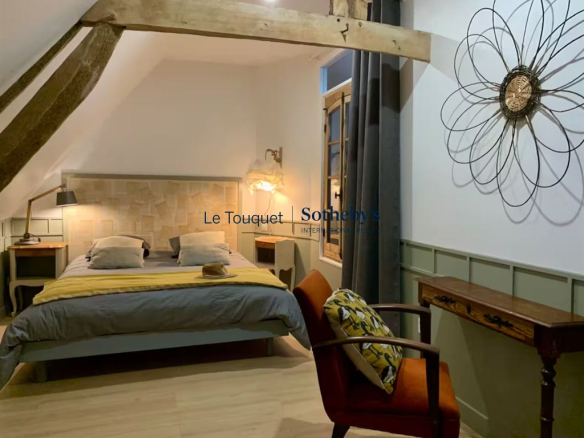 Room in a renovated property with bed, armchair and modern decor.