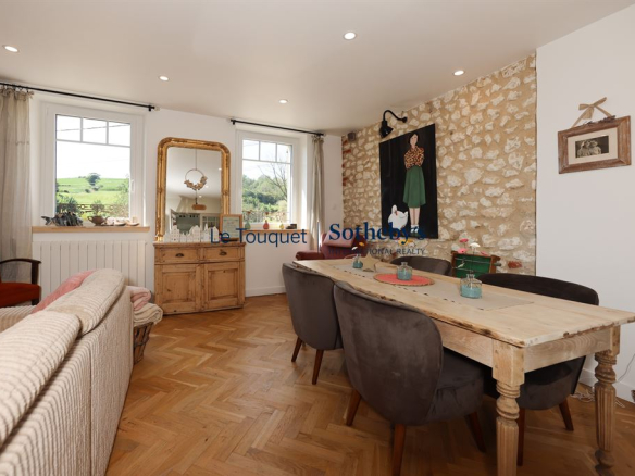 Interior of a renovated property with a living room, a dining table and stone walls.