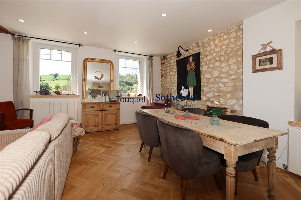 Interior of a renovated property with a living room, a dining table and stone walls.