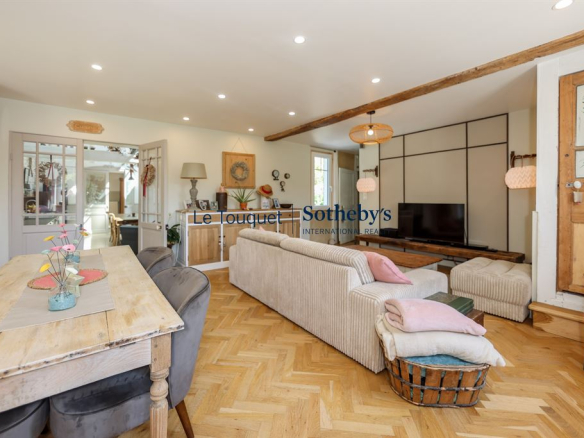 Interior of a renovated property with living room and dining room, modern lighting and warm decor.