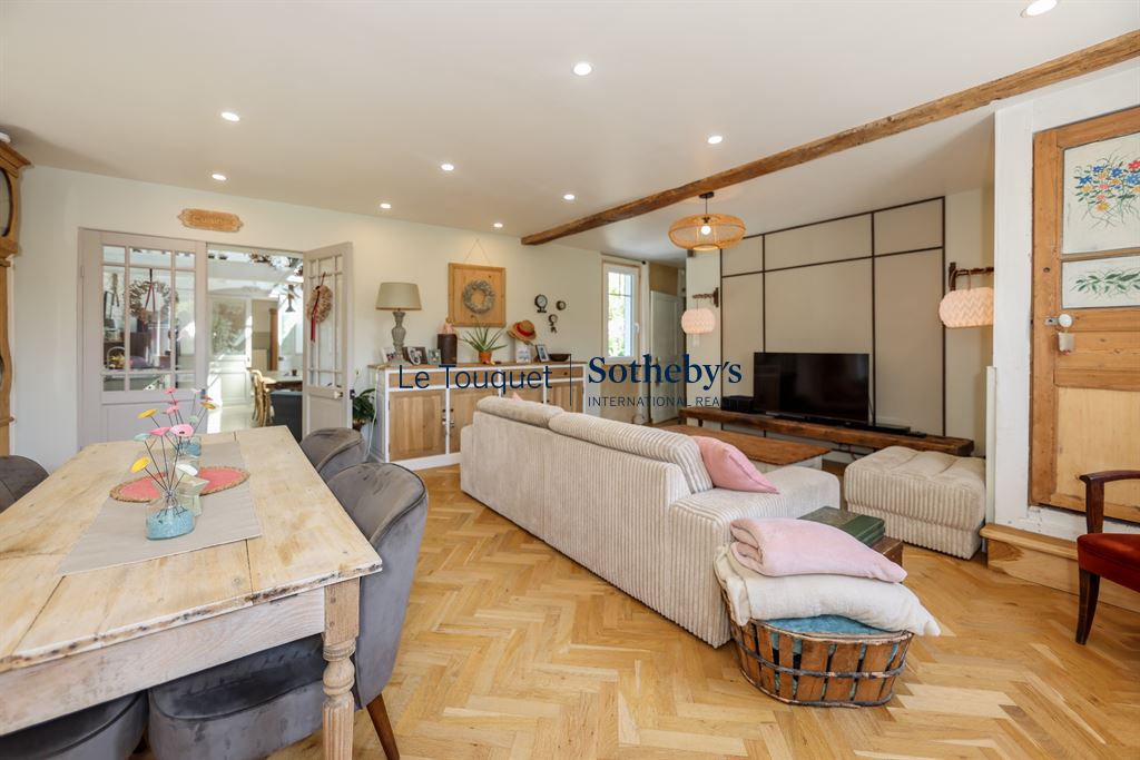 Interior of a renovated property with living room and dining room, modern lighting and warm decor.