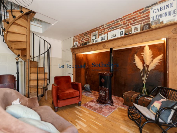Interior of a property with a spiral staircase, a comfortable living room and decorative brick elements.