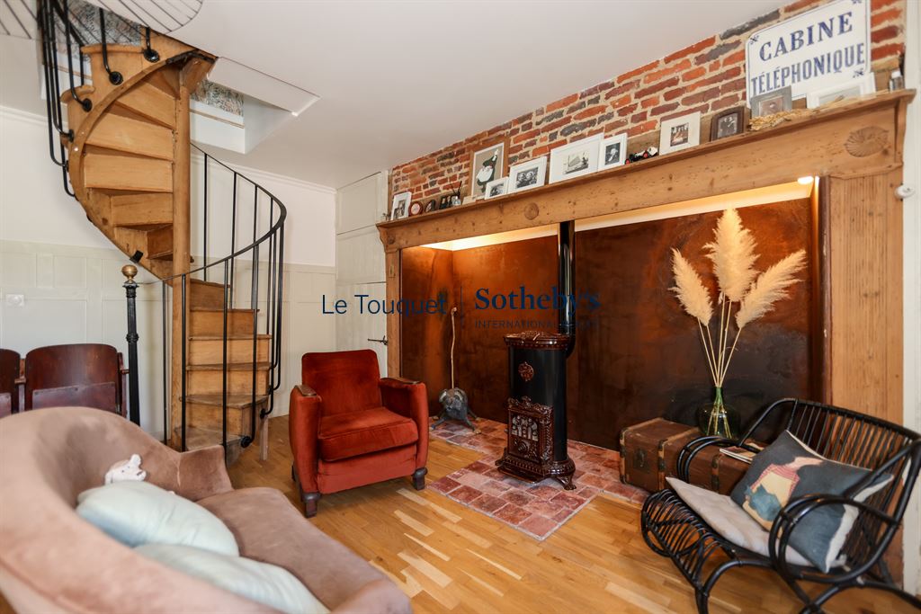 Interior of a property with a spiral staircase, a comfortable living room and decorative brick elements.