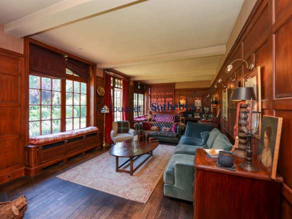 Interior of a historic property with wood paneling and windows overlooking a park.