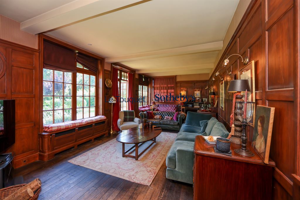 Interior of a historic property with wood paneling and windows overlooking a park.
