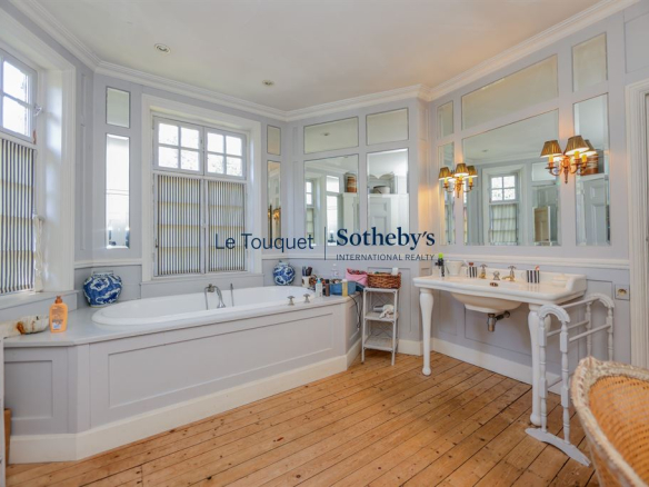 Spacious bathroom with bathtub and sink, decorated in a classic style.
