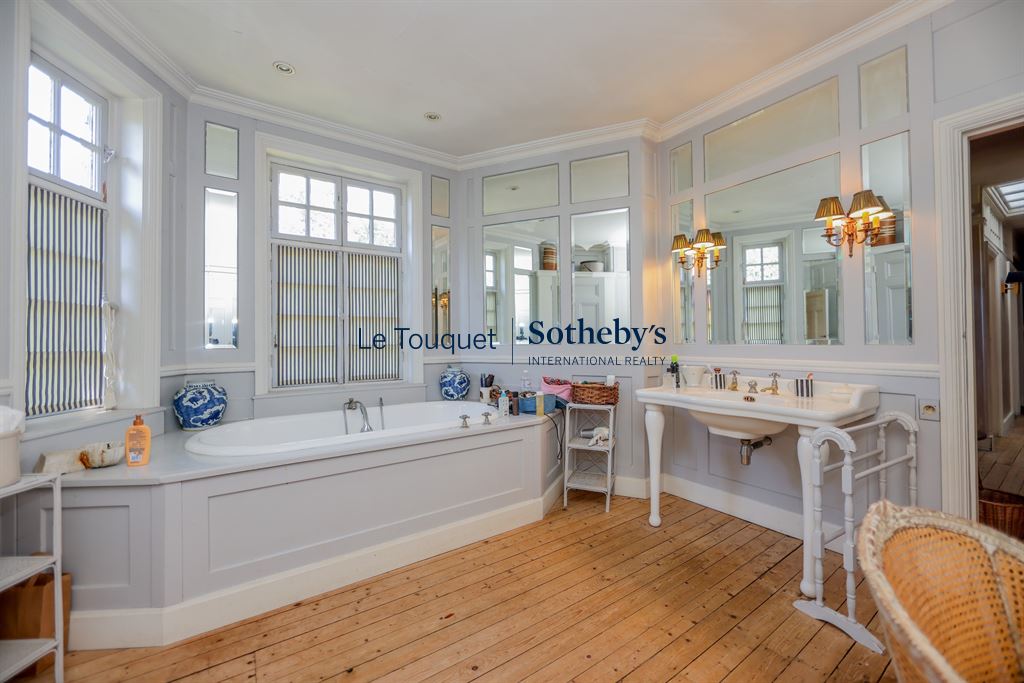 Spacious bathroom with bathtub and sink, decorated in a classic style.