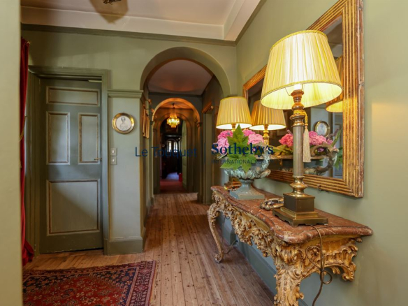 Interior of a historic property with a hallway decorated with antique lamps and furniture.