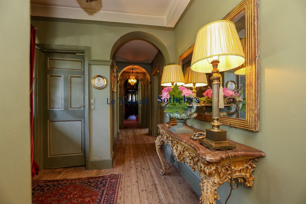 Interior of a historic property with a hallway decorated with antique lamps and furniture.