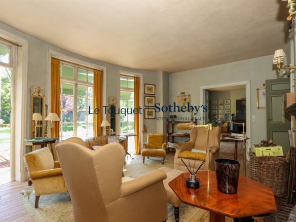 Interior of a historic property with armchairs and windows overlooking a park.