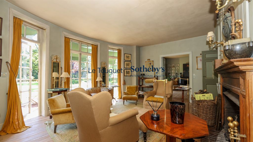 Interior of a historic property with armchairs and windows overlooking a park.