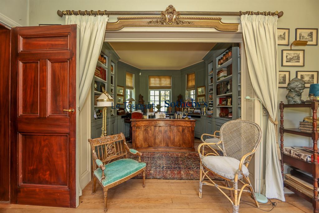 Interior of a historic property with a wooden desk and armchairs, Le Touquet-Paris-Plage.