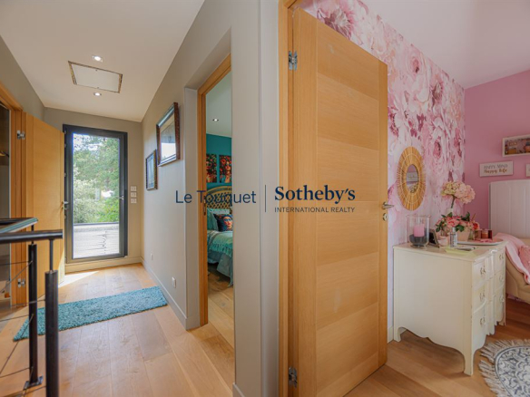 Intérieur d'une villa contemporaine avec un couloir menant à des chambres et une décoration florale.
