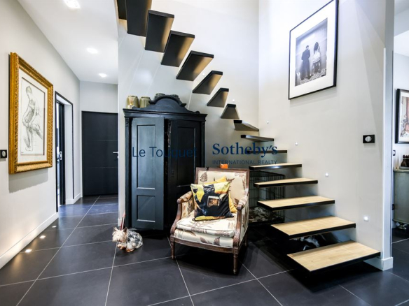 Intérieur d'une villa contemporaine avec un escalier en bois et un coin salon confortable.