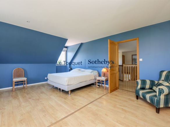 Chambre spacieuse avec murs bleus et mobilier en bois, située dans une villa à Saint-Josse.