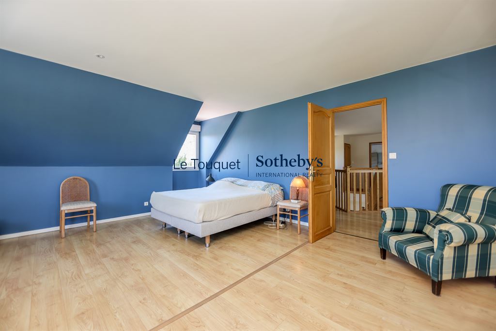 Chambre spacieuse avec murs bleus et mobilier en bois, située dans une villa à Saint-Josse.