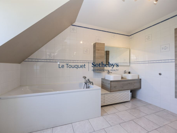 Salle de bain spacieuse avec baignoire et double vasque dans une villa à Saint-Josse.