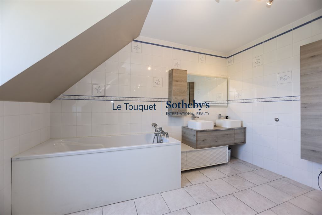 Salle de bain spacieuse avec baignoire et double vasque dans une villa à Saint-Josse.