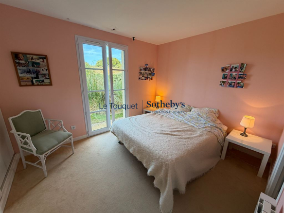 Chambre d'une villa à louer au Touquet, avec lit et fenêtre donnant sur l'extérieur.
