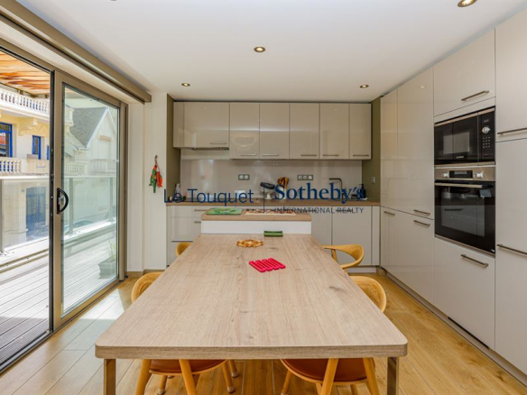 Cuisine moderne d'un appartement avec table en bois et accès à une terrasse.