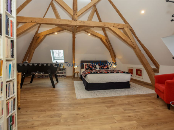 Spacious room with exposed beams, double bed and foosball table.