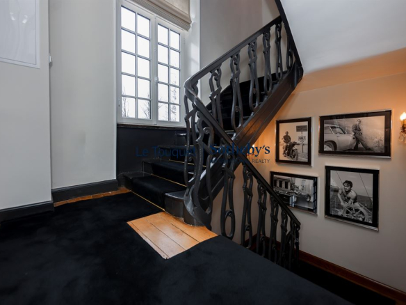 Interior staircase of a manor house with framed photos on the walls.