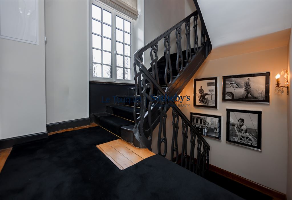 Interior staircase of a manor house with framed photos on the walls.