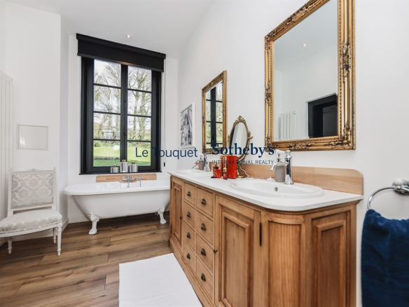Modern bathroom with bathtub, wooden vanity and gilded mirror, natural light