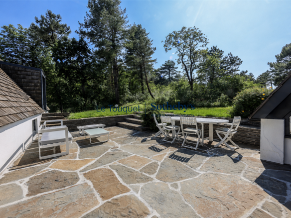 Terrasse en pierre avec mobilier de jardin, entourée de pins maritimes et d'un paysage naturel au Touquet.