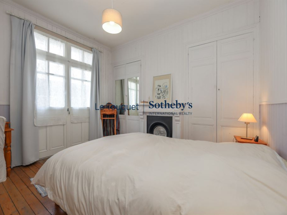 Chambre d'une villa à Le Touquet-Paris-Plage avec lit double et fenêtres lumineuses.
