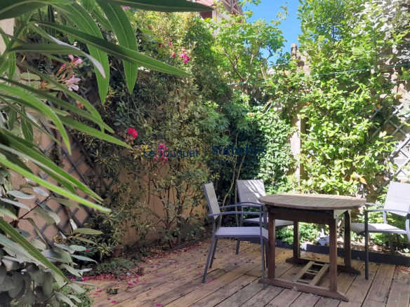 Terrasse en bois avec des chaises et des plantes verdoyantes dans une villa au Touquet-Paris-Plage.
