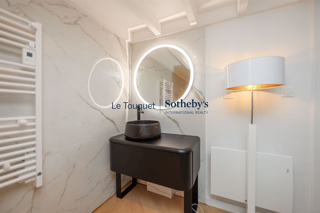 Salle de bain du duplex au Touquet Salle de bain moderne avec miroir rond et lavabo élégant dans un duplex au Touquet.