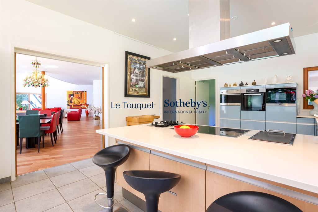 Modern kitchen with bar and view of a spacious living room.