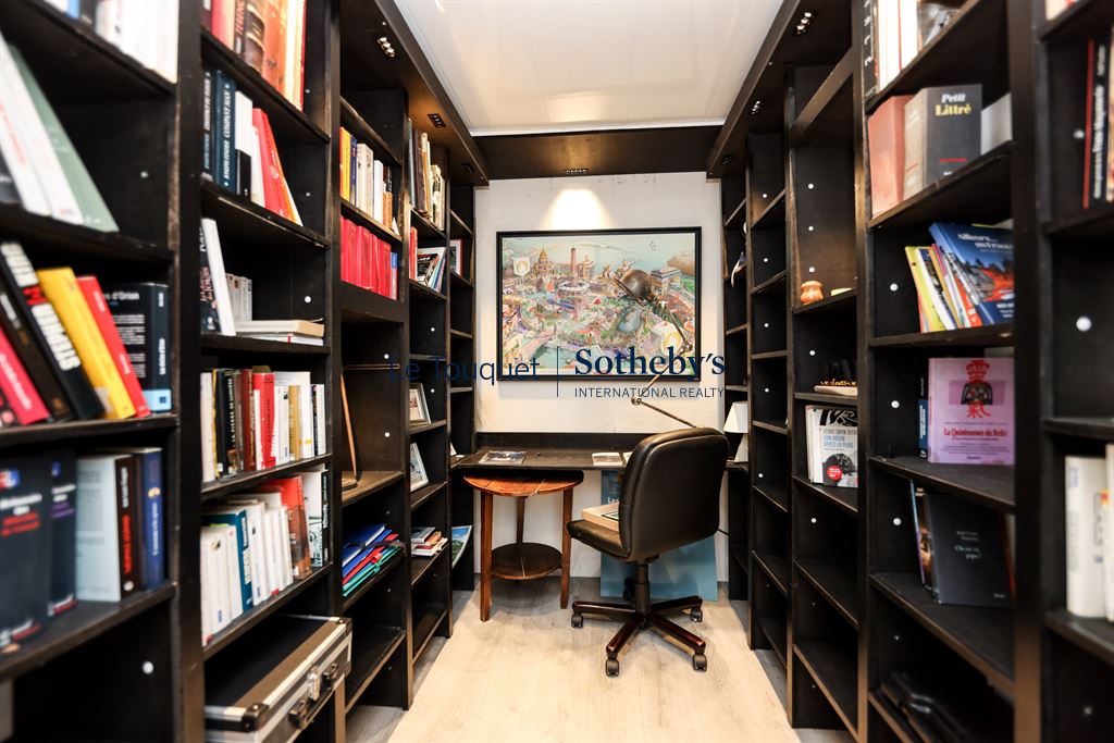 Bibliothèque du penthouse au Touquet Bibliothèque avec étagères remplies de livres et un bureau dans un penthouse au Touquet-Paris-Plage.