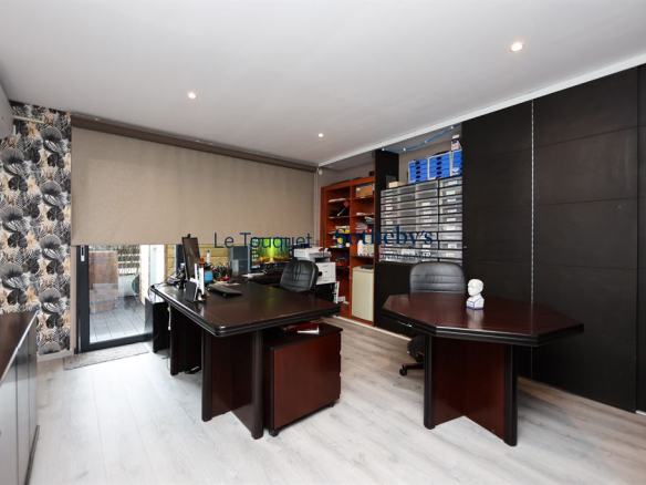 Bureau moderne avec deux grands bureaux et rangements, éclairage naturel, et accès à un espace extérieur.