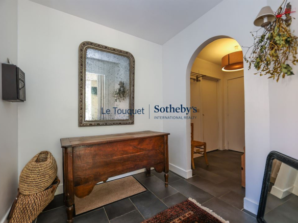 Entrance to a house with a wooden piece of furniture and a mirror, decorated in a warm style.