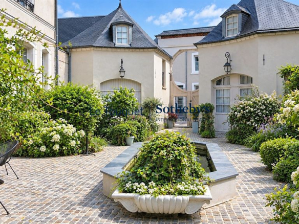 Cour intérieure d'un hôtel particulier du XVIIIe siècle à Montreuil-sur-Mer, avec des fleurs et des sièges.