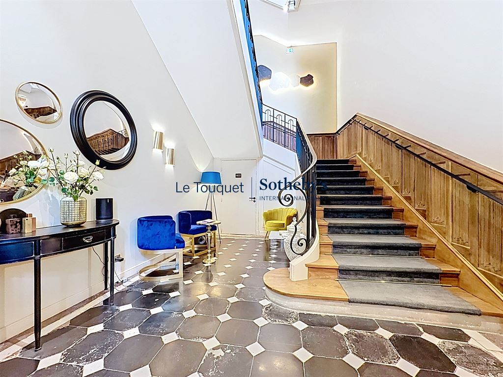 Intérieur d’un hôtel particulier à Montreuil-sur-Mer Intérieur d'un hôtel particulier avec un escalier en bois et des fauteuils colorés.